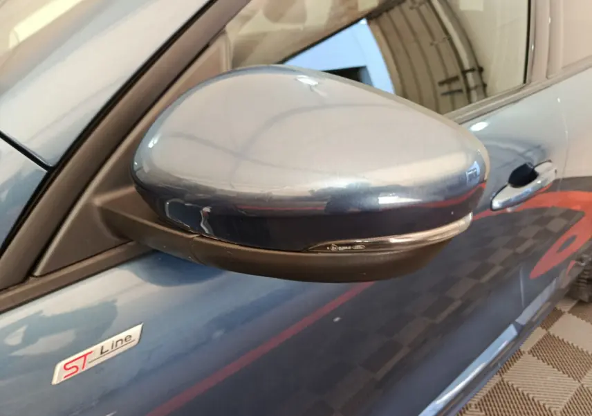 Gros plan sur le rétroviseur côté gauche bleu du Ford Kuga 2024 ST Line avec logo ST visible sur la portière.