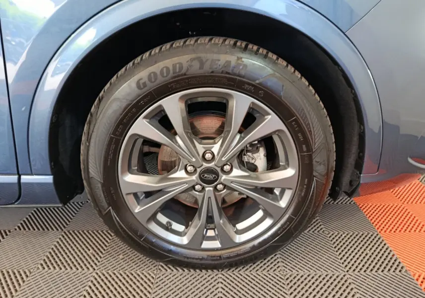 Gros plan sur la roue avant droite du Ford Kuga bleu 2024 avec jante alliage et pneu Goodyear visible.