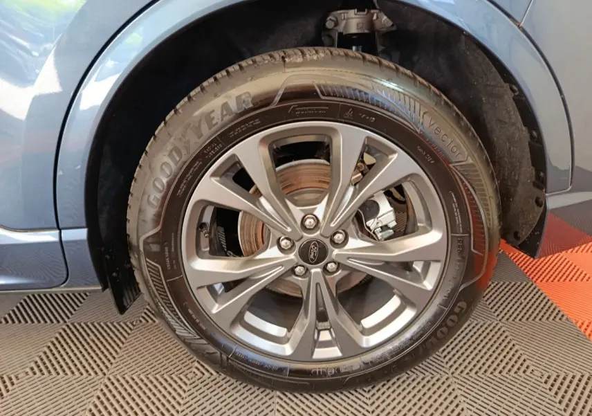 Gros plan sur la roue avant droite bleu métallisé du Ford Kuga 2024 avec jante alliage et pneu Goodyear.
