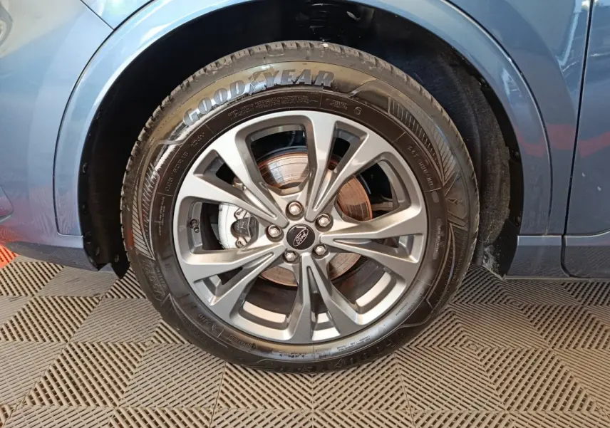 Gros plan sur la roue avant droite du Ford Kuga bleu 2024 avec jante alliage et pneu Goodyear visible.