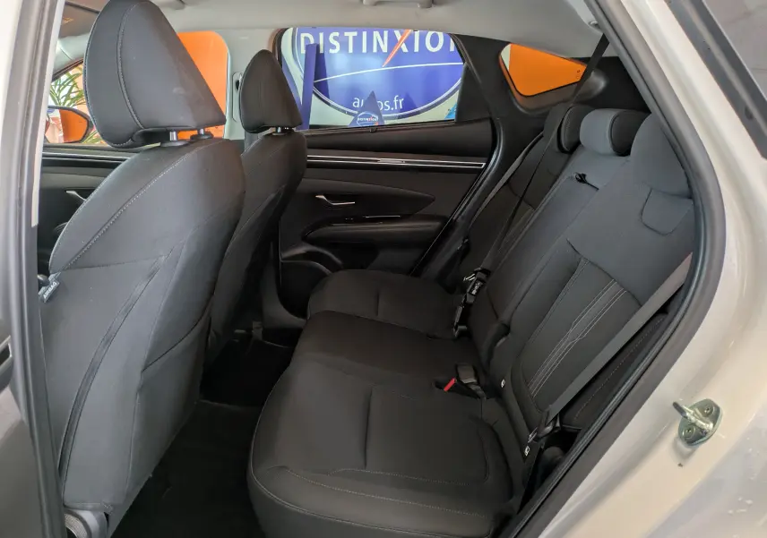 Vue intérieure côté droit des sièges arrière noirs du Hyundai Tucson blanc 2021, avec porte ouverte et garnitures modernes.