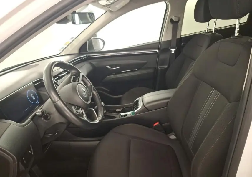 Vue 3/4 arrière droite d'un Hyundai Tucson blanc avec vitres teintées et jantes alliage, en intérieur showroom.