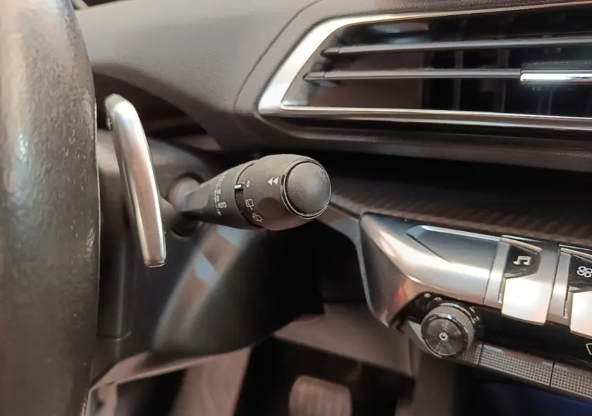 Détail intérieur du Peugeot 3008 2022 montrant la commande de clignotant et partie du tableau de bord noir.