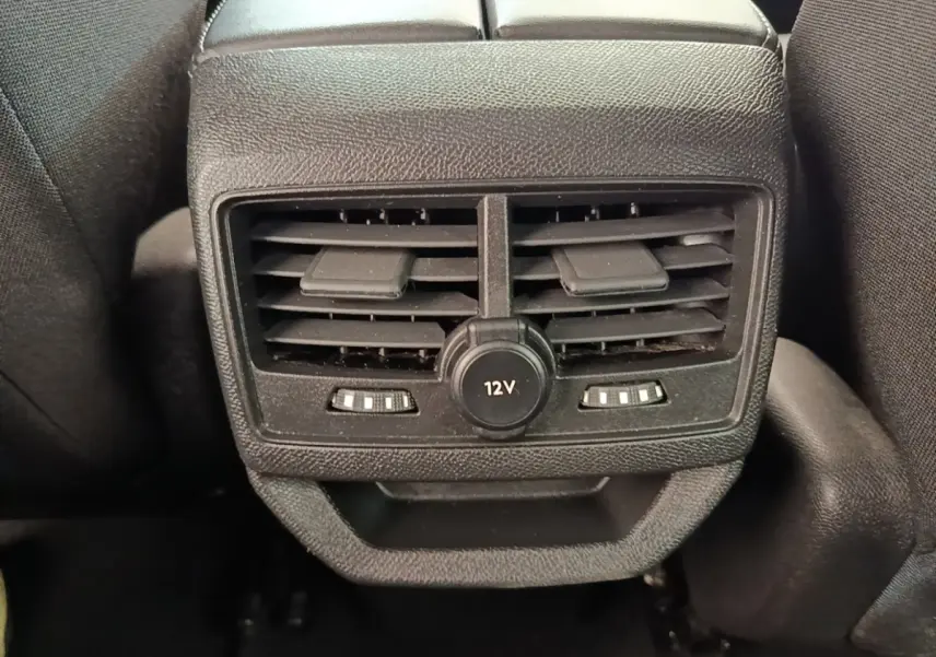 Gros plan sur la sortie d’air arrière noire avec prise 12V du Peugeot 3008 gris foncé, vue intérieure centrale.