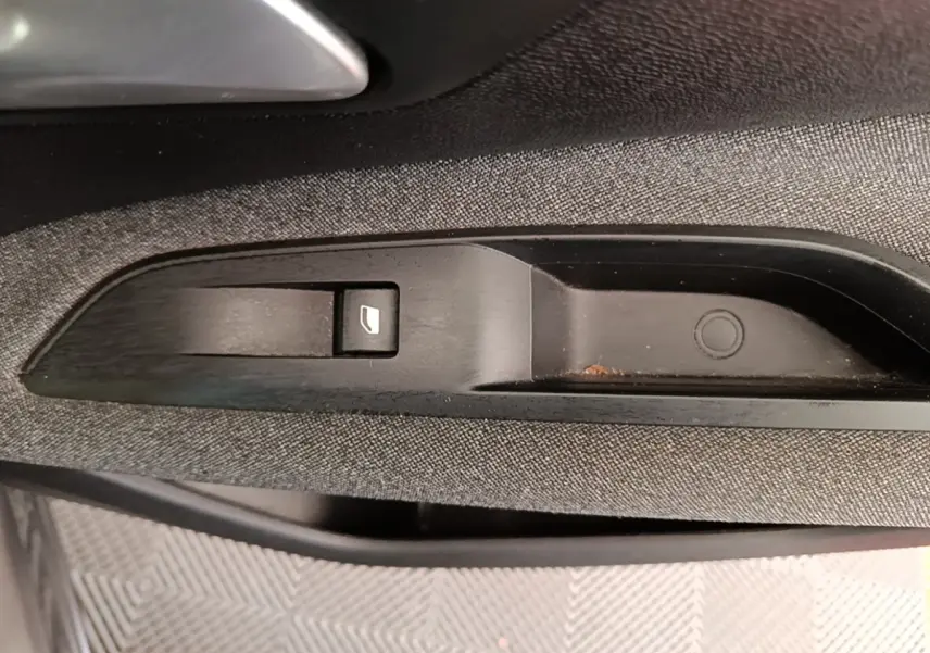 Gros plan sur le bouton de commande de lève-vitre côté conducteur dans l'habitacle gris foncé du Peugeot 3008 2022.