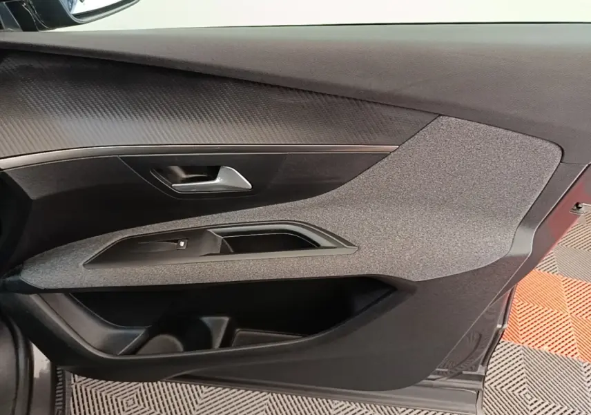 Vue intérieure côté gauche de la porte avant gris foncé du Peugeot 3008 avec poignée et habillage texturé.