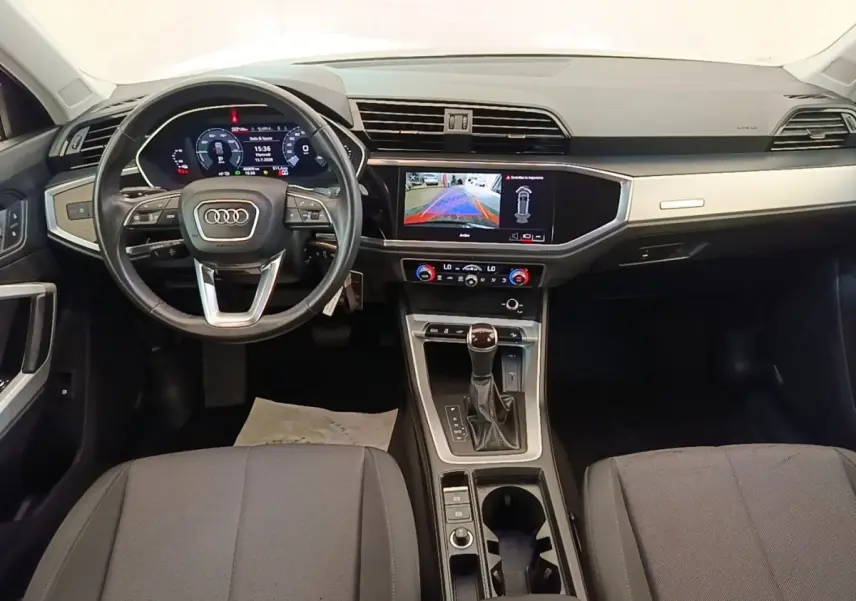 Vue intérieure avant de l'Audi Q3 45 TFSI e 2023, tableau de bord avec écran tactile et volant cuir multifonctions.