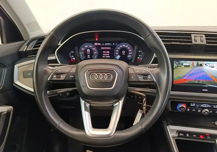 Vue intérieure centrée sur le volant cuir multifonctions noir et le tableau de bord digital de l'Audi Q3 hybride rechargeable 2023.