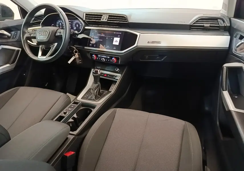 Vue intérieure avant droite de l'Audi Q3 45 TFSI E 2023 avec tableau de bord noir et écran tactile central.