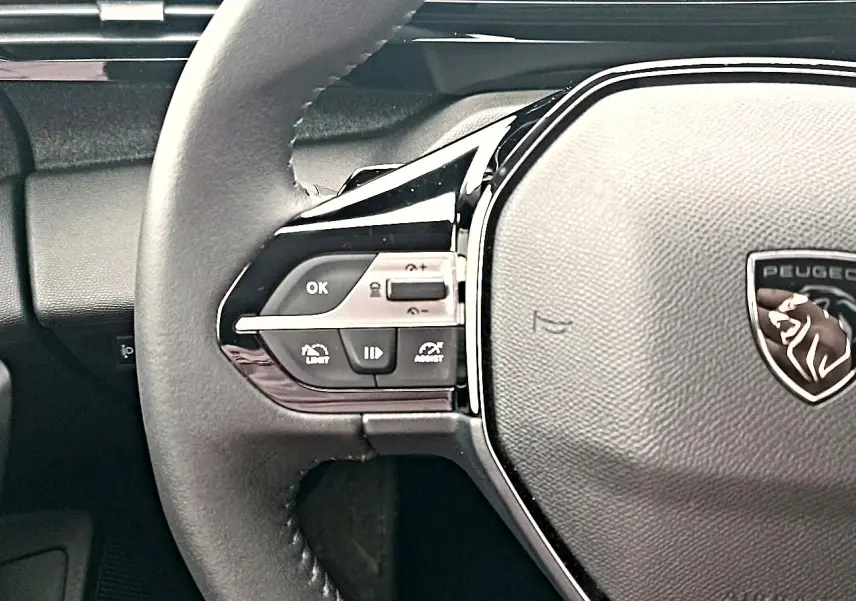 Gros plan sur le volant cuir multifonction gris du Peugeot 408 Hybrid 145 allure avec commandes intégrées côté gauche.