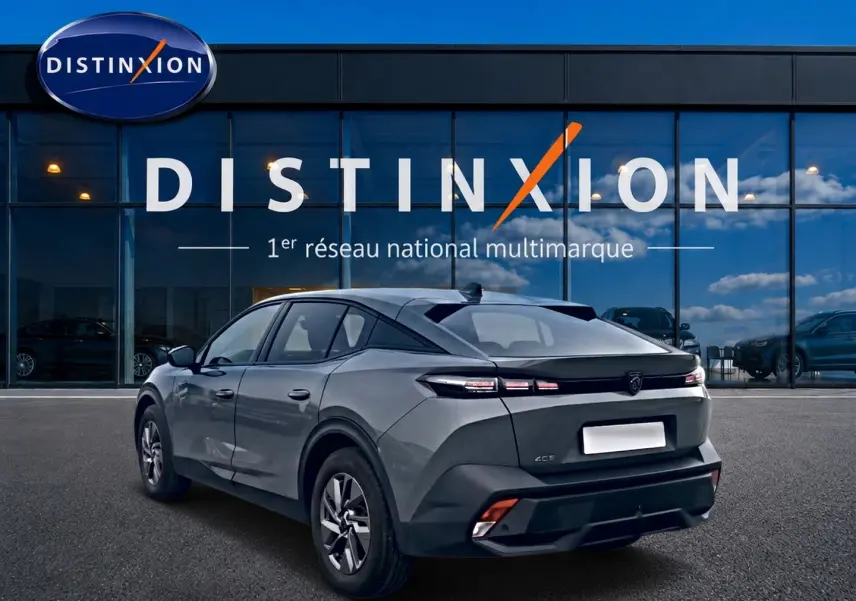 Vue 3/4 arrière droite d'une Peugeot 408 Hybrid 145 gris sellenium e devant une vitrine Distinxion.