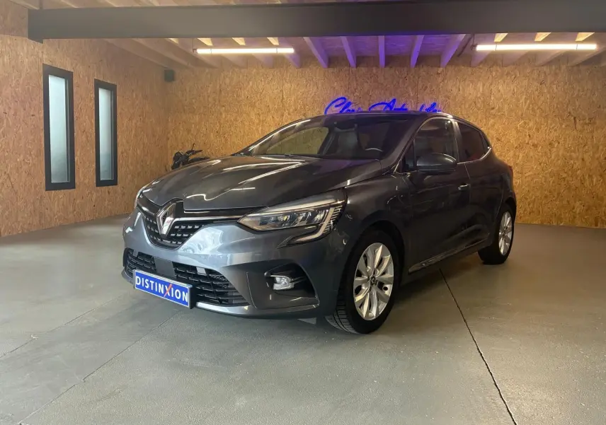 Renault Clio 1.0 TCE 100 Intens gris vue 3/4 avant droit en intérieur avec jantes alliage et phares LED.