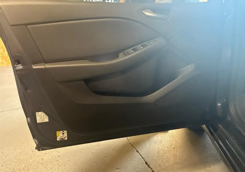 Porte avant gauche ouverte d'une Renault Clio gris 2020, montrant les commandes de vitre et le panneau intérieur noir.