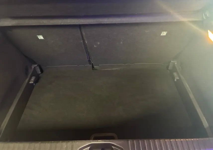 Coffre ouvert de la Renault Clio gris 2020, vue plongeante montrant l'espace de rangement vide et l'éclairage intérieur.