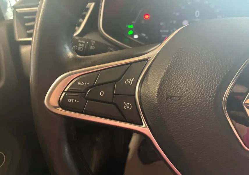 Gros plan sur les commandes de régulateur de vitesse du volant cuir noir d'une Renault Clio gris 2020.