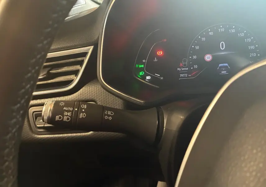 Vue rapprochée du tableau de bord et du commodo gauche de la Renault Clio gris 2020, affichant le compteur digital et témoins lumineux.