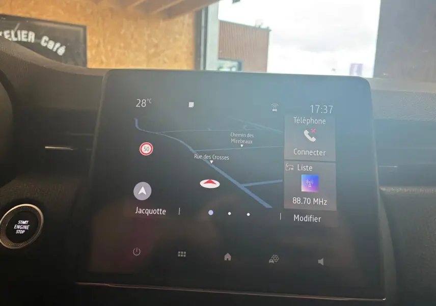Écran tactile central du tableau de bord de la Renault Clio gris, affichant la navigation et la radio à 17h37.