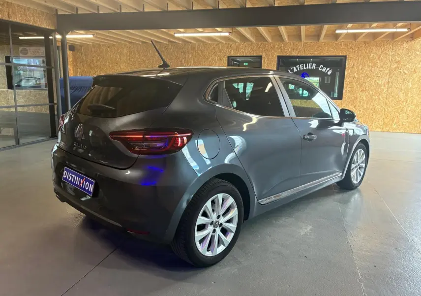 Vue 3/4 arrière droite d'une Renault Clio gris métallisé 2020, compacte et élégante, en intérieur showroom.