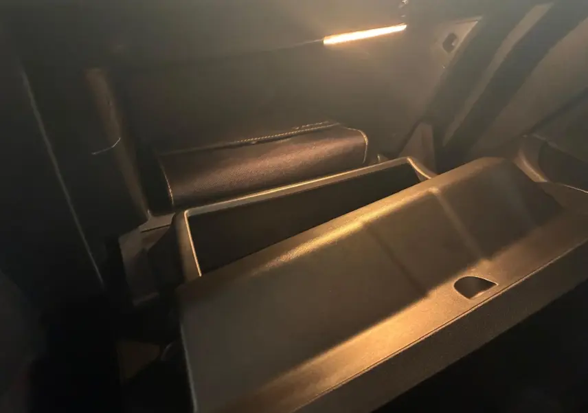 Gros plan sur la boîte à gants ouverte de la Renault Clio gris 2020, éclairage intérieur tamisé mettant en valeur le rangement.