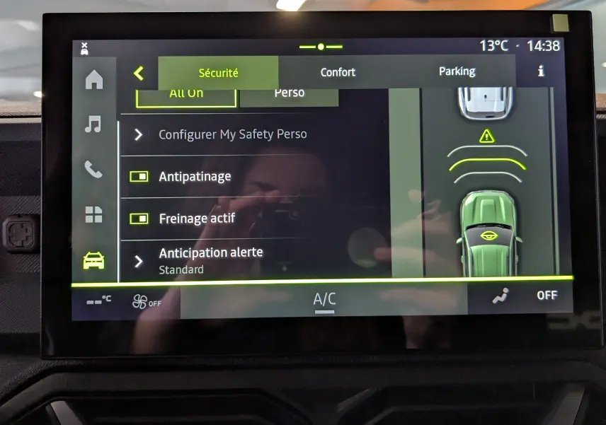 Écran tactile du tableau de bord du Dacia Duster Hybrid 140 Journey montrant les réglages de sécurité et assistance au stationnement.