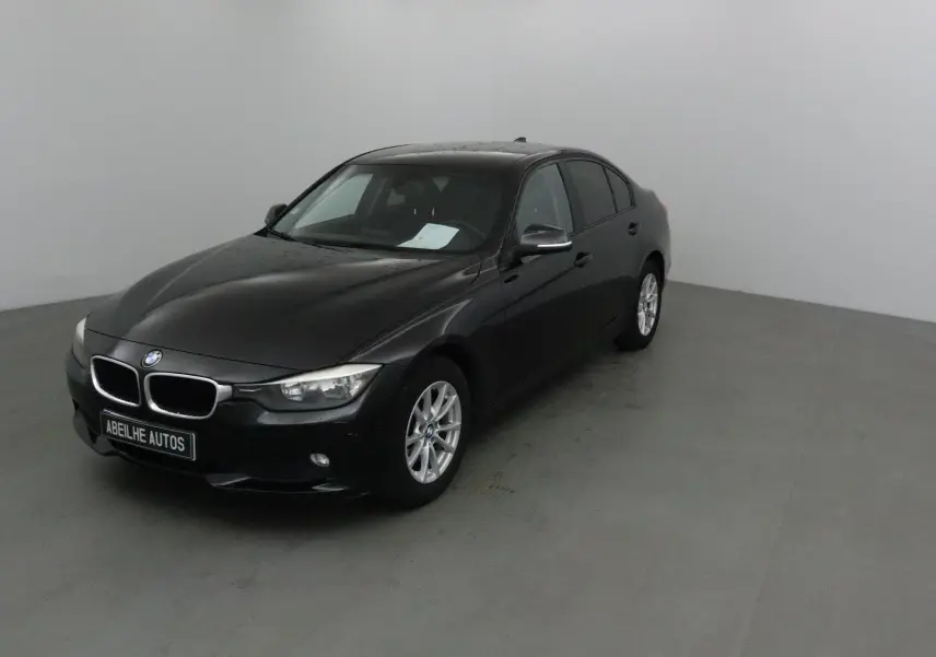 BMW Série 3 316D noire vue en 3/4 avant droit dans un studio, avec jantes alliage et calandre chromée.