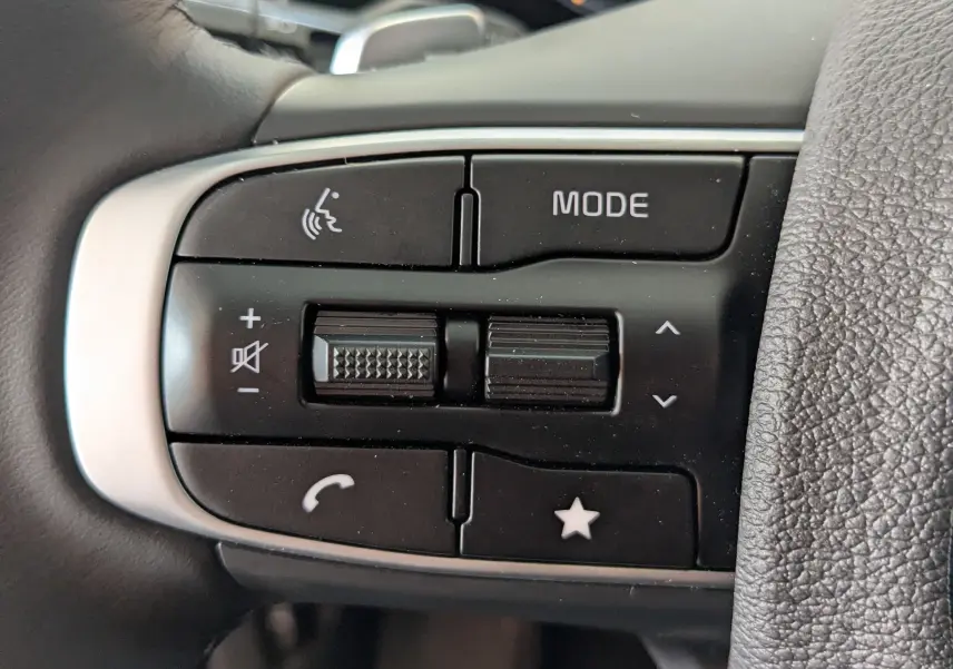 Gros plan sur les commandes multifonctions noires à gauche du volant du Kia Sportage blanc 2025.