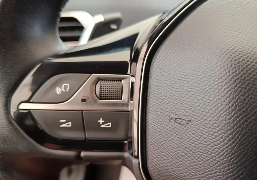 Gros plan sur le volant cuir noir du Peugeot 3008, montrant les commandes multifonctions côté gauche.