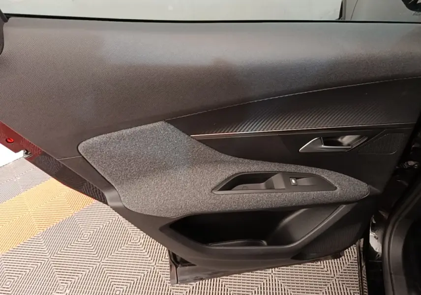 Porte intérieure côté gauche du Peugeot 3008 noir, avec habillage tissu gris et insert imitation carbone.