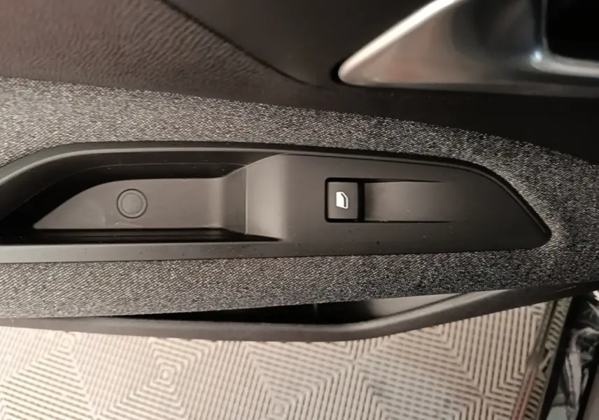 Détail de la commande d'ouverture de la trappe à carburant sur la porte intérieure d'un Peugeot 3008 noir.
