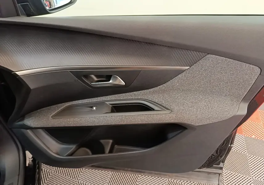 Vue intérieure côté gauche de la porte avant d’un Peugeot 3008 noir avec habillage tissu gris et poignée argentée.