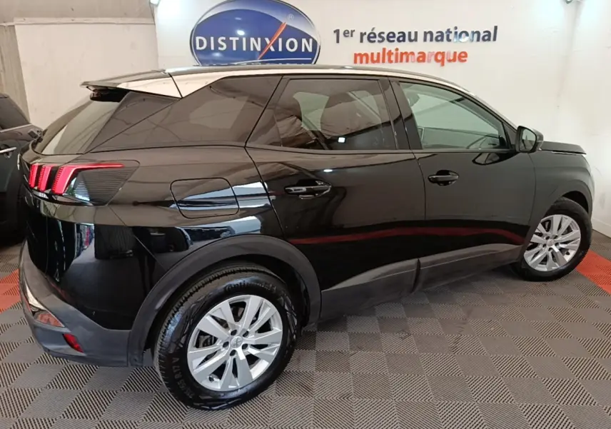 Vue côté droit arrière d’un Peugeot 3008 noir brillant avec feux arrière à griffes LED en intérieur showroom.