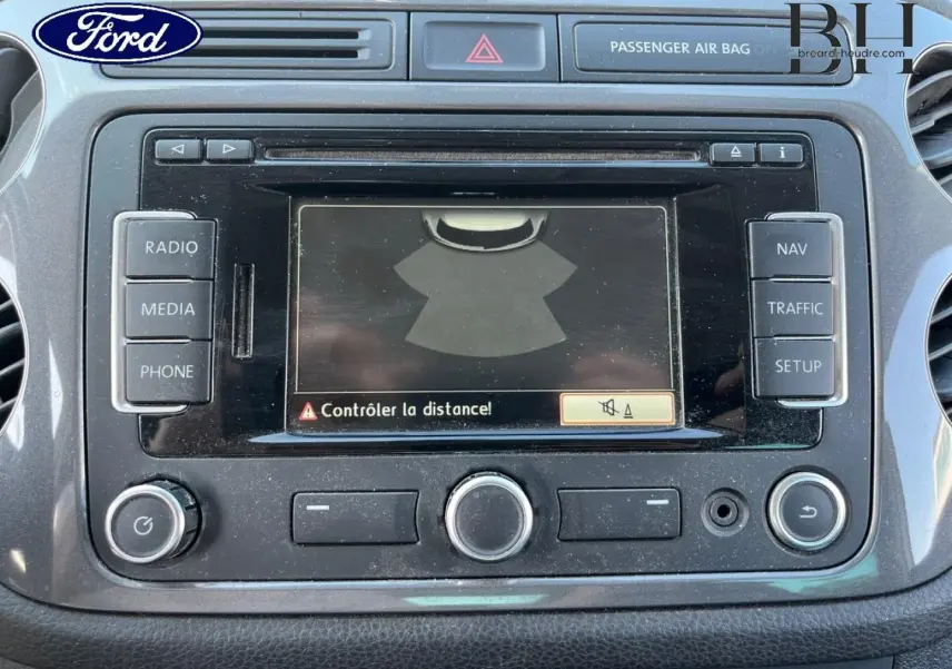 Écran tactile central du tableau de bord d’un Volkswagen Tiguan blanc, affichant un avertissement de distance.