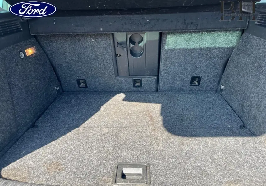 Coffre ouvert d'un Volkswagen Tiguan blanc, vue intérieure montrant la moquette grise et la trappe à skis centrale.