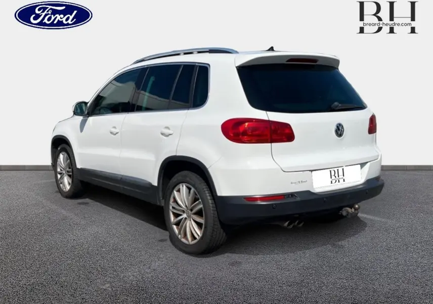 Volkswagen Tiguan blanc Candy vu en 3/4 arrière droit avec barres de toit et jantes alu 17 pouces.