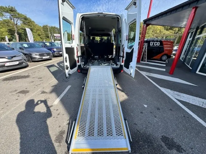 Vue arrière d'un Renault Master Combi blanc avec rampe d'accès déployée pour aménagement TPMR.