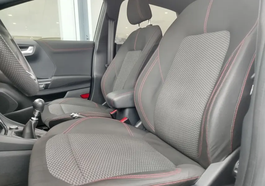 Vue intérieure côté gauche du Ford Puma 1.0 EcoBoost 125ch ST-Line, sièges noirs avec surpiqûres rouges et tissu texturé.