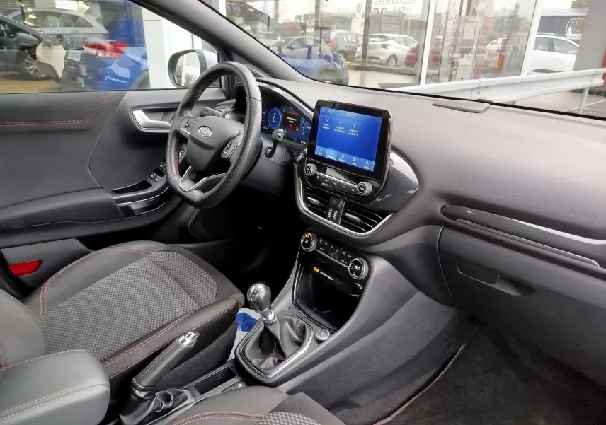 Intérieur côté conducteur du Ford Puma gris, tableau de bord moderne avec écran tactile et boîte manuelle visible.