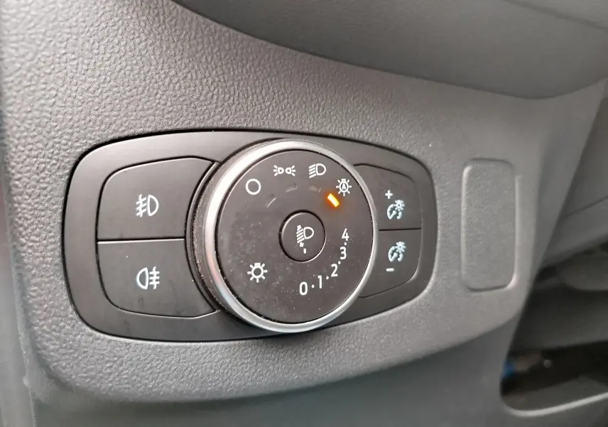 Gros plan sur le bouton de réglage des phares du Ford Puma 1.0 EcoBoost 125ch gris, avec indicateur orange allumé.