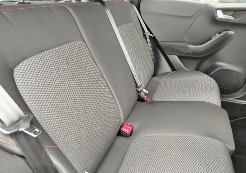 Vue intérieure du siège arrière droit du Ford Puma 2021, tissu gris à motifs avec surpiqûres rouges et ceinture de sécurité.