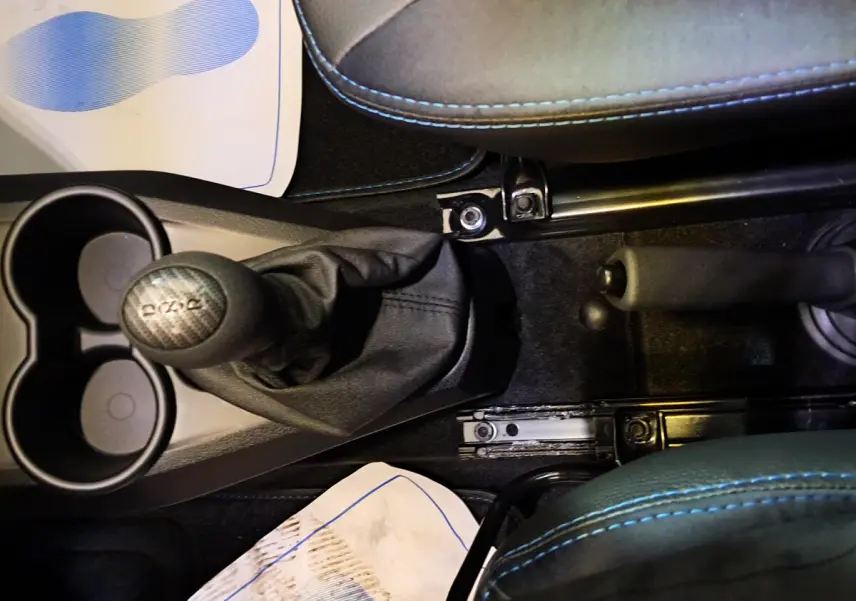 Vue plongeante sur la console centrale intérieure de l'AIXAM AMBITION 2026 avec levier de vitesse et frein à main noirs.