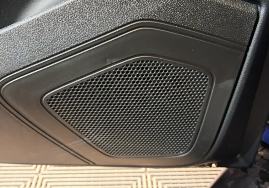 Gros plan sur le haut-parleur intégré à la porte côté conducteur d’une Aixam Ambition bleu 2026.