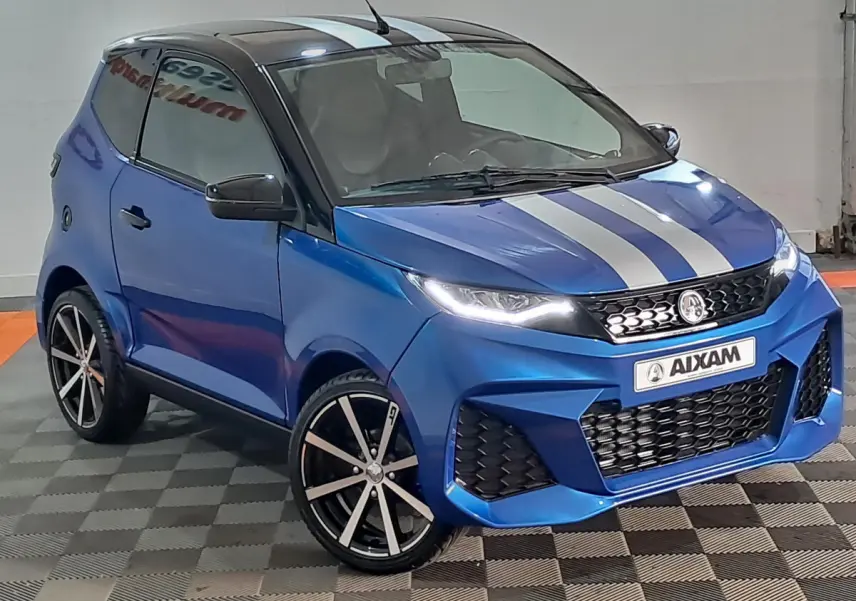 Vue 3/4 avant droite de l'AIXAM AMBITION bleu 2026 avec bandes grises, jantes noires et rétroviseur caméra côté conducteur.