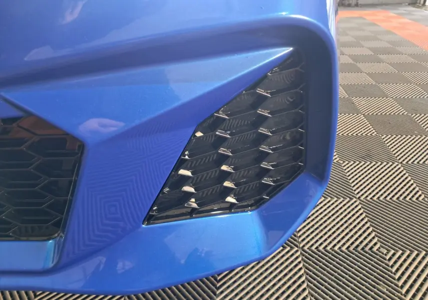 Gros plan sur la calandre avant droite bleue de l'AIXAM AMBITION 0.5 CITY GTO avec motif hexagonal noir.