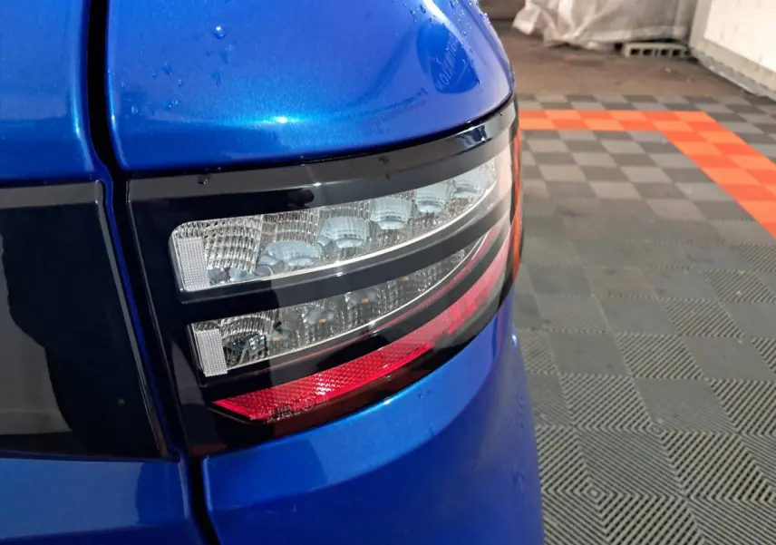 Gros plan sur le feu arrière droit bleu métallisé de l'AIXAM AMBITION 0.5 CITY GTO 2026 dans un garage.