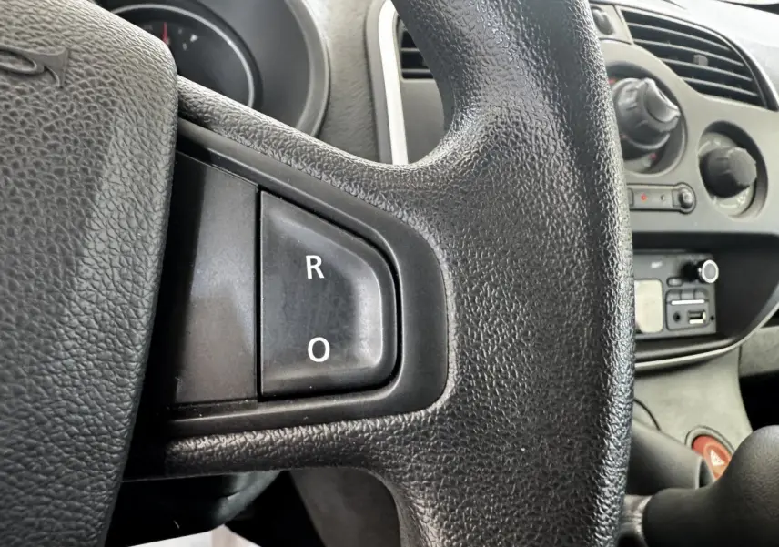 Gros plan sur le volant multifonctions noir du Renault Kangoo 2016, avec tableau de bord et commandes visibles en arrière-plan.