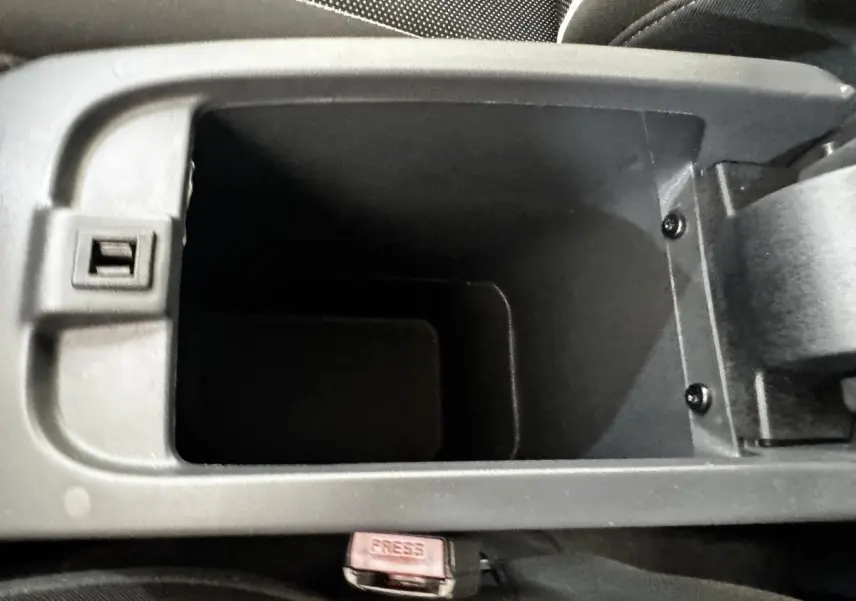 Gros plan sur le rangement central ouvert de l’habitacle du Renault Kangoo blanc, montrant le compartiment vide.
