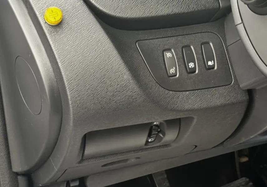 Vue intérieure du tableau de bord côté conducteur du Renault Kangoo blanc, avec commandes des aides à la conduite et réglage des phares.