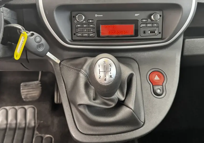 Vue rapprochée de la console centrale du Renault Kangoo blanc 2016, avec levier de vitesse manuel et radio affichant 102.40 MHz.