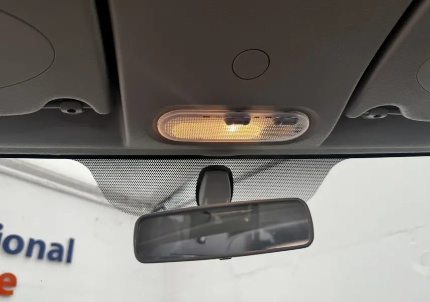 Vue intérieure centrée sur le plafonnier allumé et le rétroviseur intérieur du Renault Kangoo blanc de 2016.