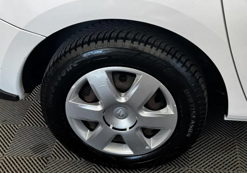 Gros plan sur la roue arrière droite d’un Renault Kangoo blanc, montrant le passage de roue et le pneu toutes saisons.
